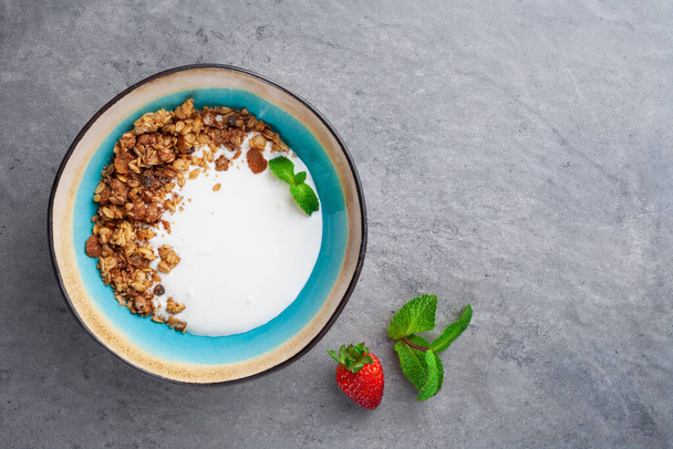 Porção de iogurte natural com granola de cereais caseira em tigela azul - Foto, Imagem