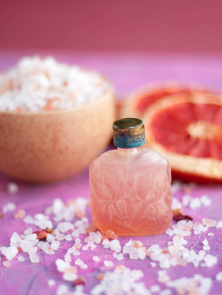 Zamknij zdjęcie butelki olejku eterycznego i naturalnych składników na różowym tle - Zdjęcie, obraz