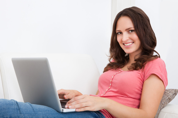 Woman Sitting On Couch Using Laptop - Foto, immagini