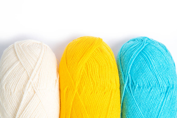 tres madejas de hilos de lana sobre un fondo blanco, blanco, amarillo y azul, espacio de copia de posición horizontal desde la parte superior
 - Foto, imagen