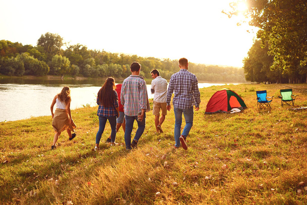 Friends have fun running along the lake on a picnic. - Zdjęcie, obraz
