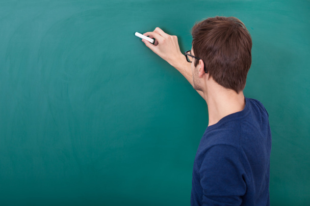 Male Student Writing On Chalkboard - Foto, afbeelding