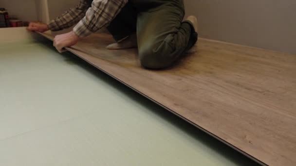 Työntekijä laittaa uuden laminaatin lattialle. Asetan lattiapäällysteen. Mestari talossa.
. - Materiaali, video