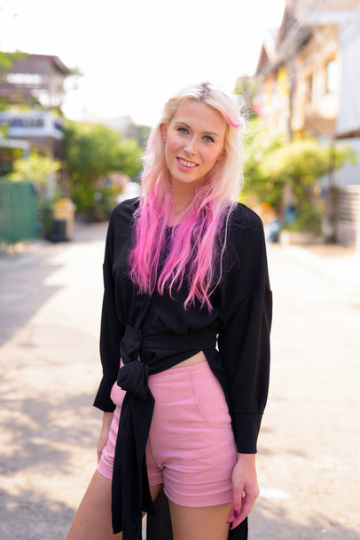 Portrait of young beautiful blonde woman exploring the city streets outdoors - 写真・画像