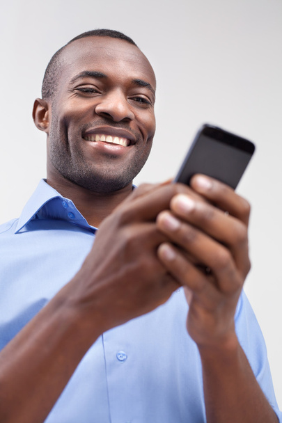Black man typing on the mobile phone and smiling - 写真・画像