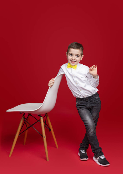 Cute schoolboy standing near chair - Фото, зображення