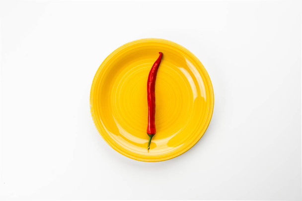 Yellow plate with red Chili pepper, top view - Valokuva, kuva