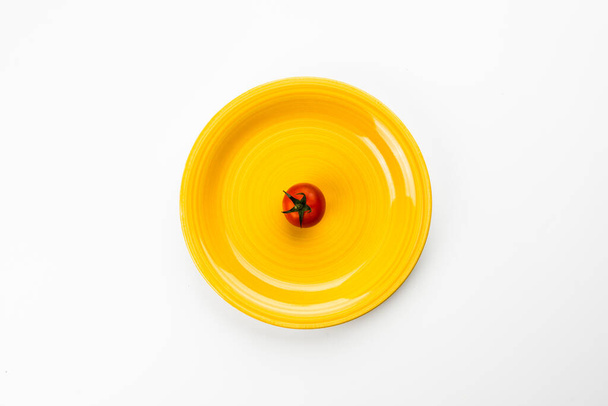 Yellow plate with red tomato, top view - Zdjęcie, obraz