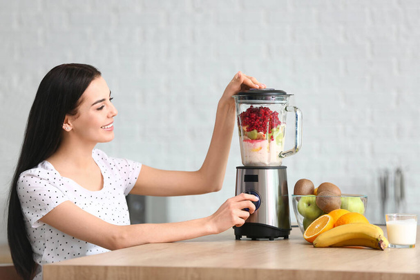 Junge Frau macht Frucht-Smoothie in Küche zu Hause - Foto, Bild