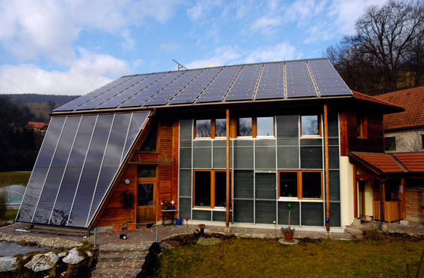 huis met zonnepanelen op het dak op een herfstdag - Foto, afbeelding