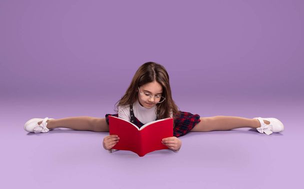 Schoolgirl doing splits and reading textbook - Fotoğraf, Görsel