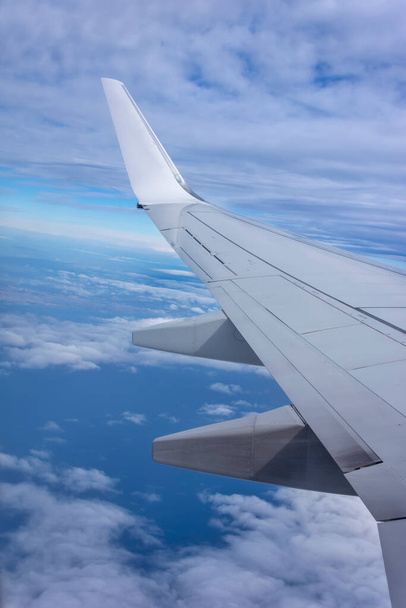 Widok z lotu ptaka nad chmurami i niebem. Skrzydło samolotu przelatuje nad tropikalną wyspą. Widok z okna samolotu chwili emocjonalnej podczas podróży międzynarodowych dookoła świata. - Zdjęcie, obraz