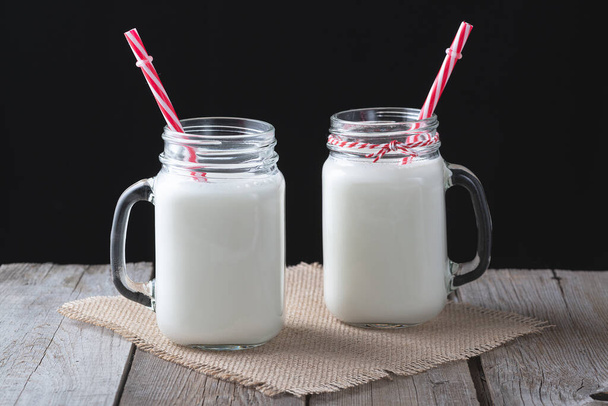 Skleněné poháry s mlékem na dřevěném venkovském pozadí - Fotografie, Obrázek