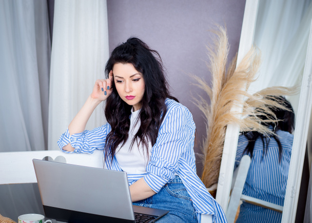 Dívka na volné noze sedí na pohovce a pracuje u laptopu. Práce na vzdáleném webu. - Fotografie, Obrázek