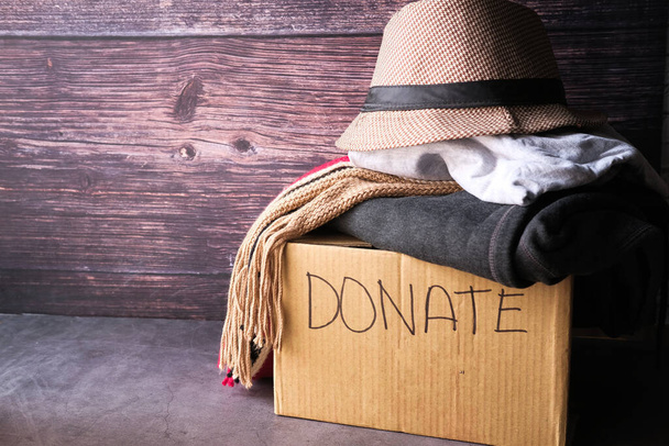 Donatie doos met donatie kleding op een houten tafel . - Foto, afbeelding