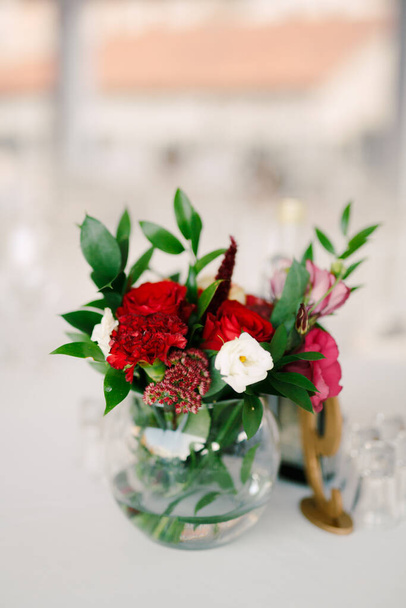 Vidrio redondo lisa transparente con rosas y claveles rojos
 - Foto, imagen