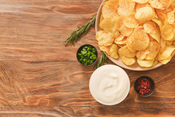Bowl with tasty sour cream and potato chips on table - Fotó, kép