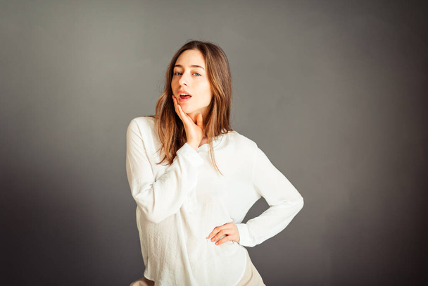 Young girl in a white shirt on a gray background. French woman in white blouse on a background of gray walls. Without retouching and makeup. - Photo, Image