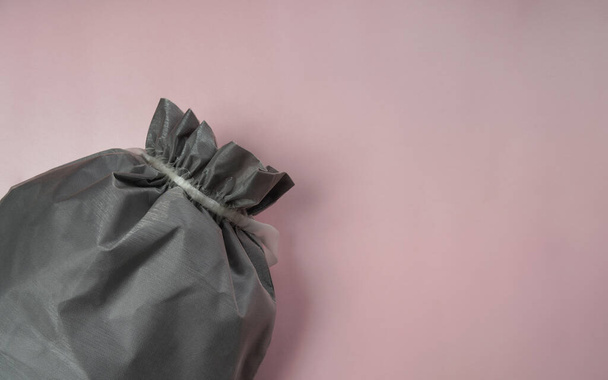 Κάτοψη του υφάσματος γκρι τσάντα σε ροζ χρώμα φόντο με αντίγραφο χώρου - Φωτογραφία, εικόνα