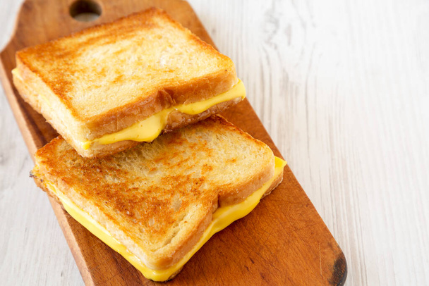 Homemade Grilled Cheese Sandwich on a rustic wooden board on a white wooden table, low angle view. Copy space. - Photo, Image