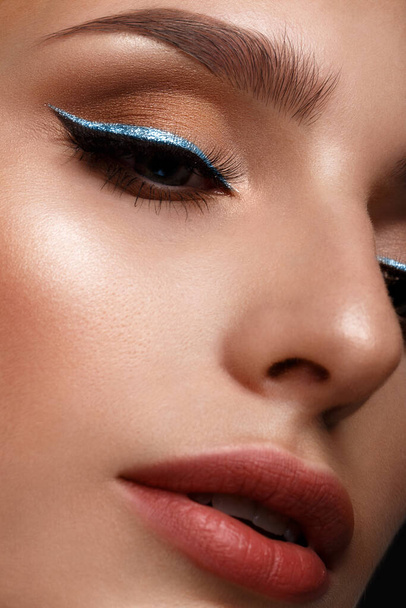 Beautiful girl with sexy lips and classic makeup with cosmetic blue eyeliner . Beauty face. - Foto, imagen