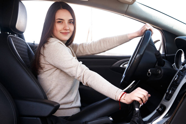 Young beautiful happy woman sitting at the wheel new car. - Foto, Imagen