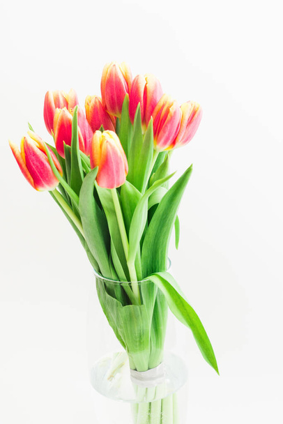 Bouquet of pink tulips flowers in glass vase on white background. Vertical shot - Foto, imagen