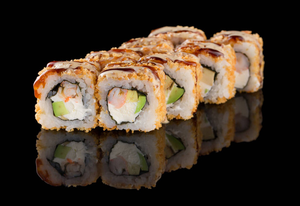 Sushi roll with shrimp, avocado, cheese, omelet breading isolated on black background with reflection - Fotó, kép