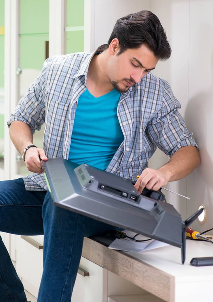 Молодий чоловік чоловік ремонтує телевізор вдома
 - Фото, зображення