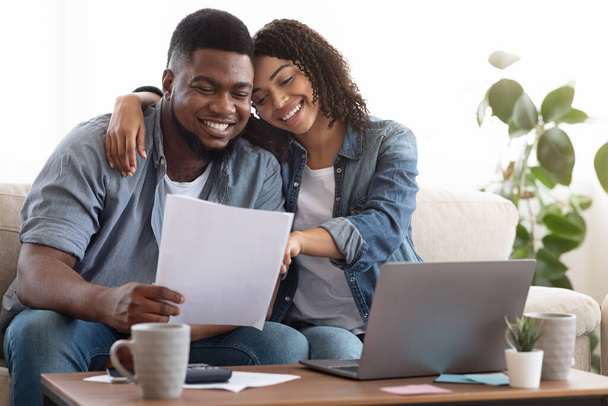 Family insurance. Black couple reading documentation at home, checking agreement together - Photo, Image