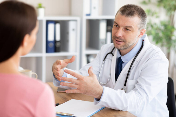Mužský zkušený lékař mluví se svou pacientkou - Fotografie, Obrázek