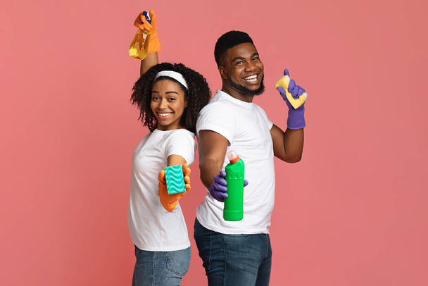 Alegre limpieza de primavera. alegre pareja negra posando con esponjas y detergentes
 - Foto, Imagen