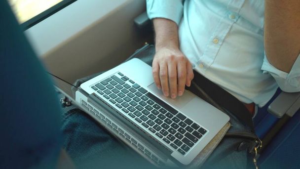 Top view of an unrecognizable businessman s hands using his laptop while he is riding a train.  - Φωτογραφία, εικόνα