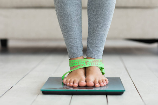 Femme debout sur des balances de poids, avec ruban à mesurer sur les jambes à l'intérieur
 - Photo, image