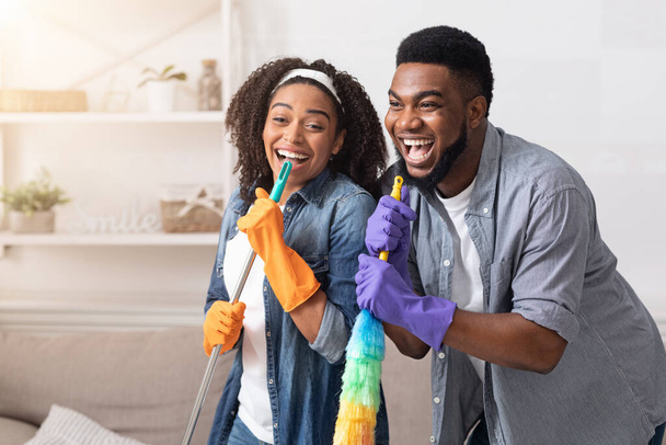 Lavori domestici con divertimento. Coppie africane pulire casa insieme, cantare e ingannare
 - Foto, immagini