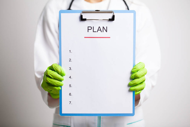 Doctor in a white coat holds a letter with a plan of action - Photo, image