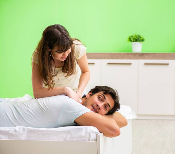 Mujer haciendo masaje a su marido en el dormitorio - Foto, Imagen