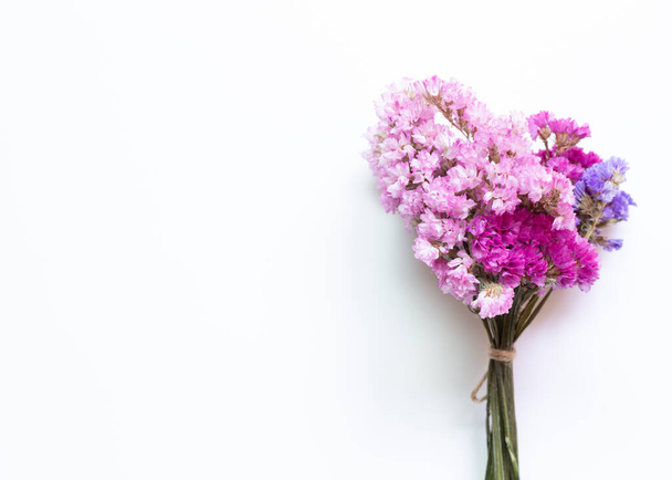 Rózsaszín lila statice virágok csokor fehér alapon. Virágkompozíció, lapos fektetés, felülnézet - Fotó, kép