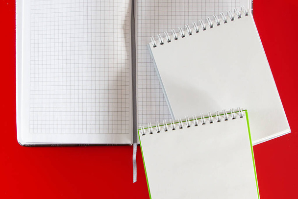 Layout minimalista per il design. Forniture per ufficio - quaderni e penne su sfondo rosso. Apri il quaderno vuoto per le note su sfondo rosso - Foto, immagini