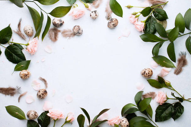 Easter concept. Easter of circle frame for your banner with feathers, branches and buds rose and quail eggs on white background with place for text. Top view. Flat lay. Postcard for Spring Holidays - Фото, зображення