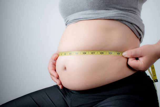 Mujer obesa o con sobrepeso midiendo su grasa abdominal
. - Foto, imagen