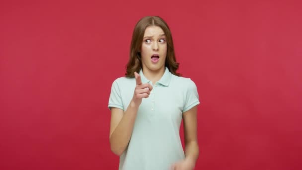 Hey you! Happy surprised woman in polo t-shirt pointing fingers to camera and looking with amazement, noticing and showing something unbelievable and shocking. studio shot isolated on red background - 映像、動画