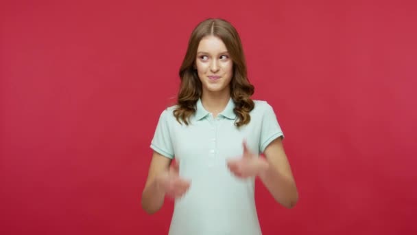 Very good job! Happy young brunette woman in polo t-shirt showing thumbs up, gesturing like to express support and satisfaction with excellent service. indoor studio shot isolated on red background - Imágenes, Vídeo