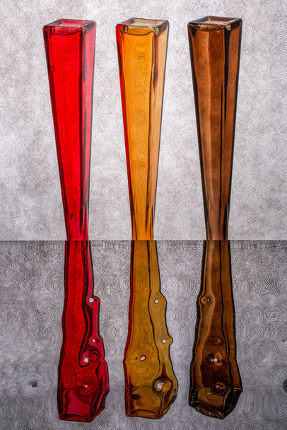 Натюрморт с перевернутыми цветными бутылками на отражающей поверхности
 - Фото, изображение