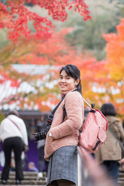 Happy woman enjoying with colorful leaves in the garden, Asian traveler visit Eikando temple, famous for tourist attractions in Kyoto, Japan. Autumn season, vacation, Sightseeing and travel concept - Photo, image
