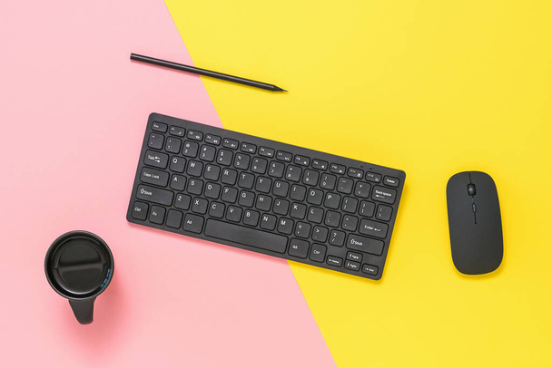 Black keyboard, mouse, pencil and coffee Cup on red and yellow background. - Photo, Image