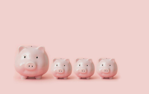Four piggy bank one large and three small stand on pink background. Concept of successful investments giving dividends and interest. Advertising space - Foto, Imagem