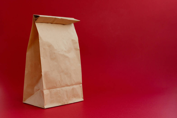 brown paper craft bag for shopping on a red background - Foto, afbeelding