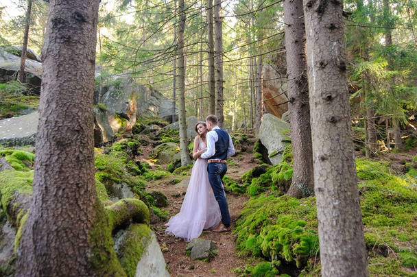 Ein attraktives Brautpaar, ein glücklicher und freudiger Moment. Ein Mann und eine Frau rasieren und küssen sich in Urlaubskleidung. Hochzeitszermonie im böhmischen Stil im Wald an der frischen Luft. - Foto, Bild