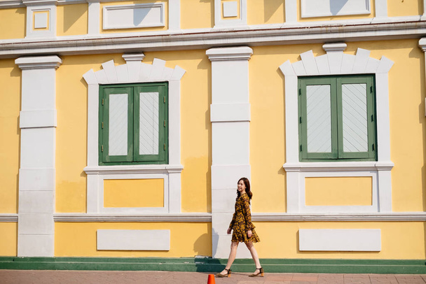Thai woman walking on sidewalk with historical building at the back. - Photo, image
